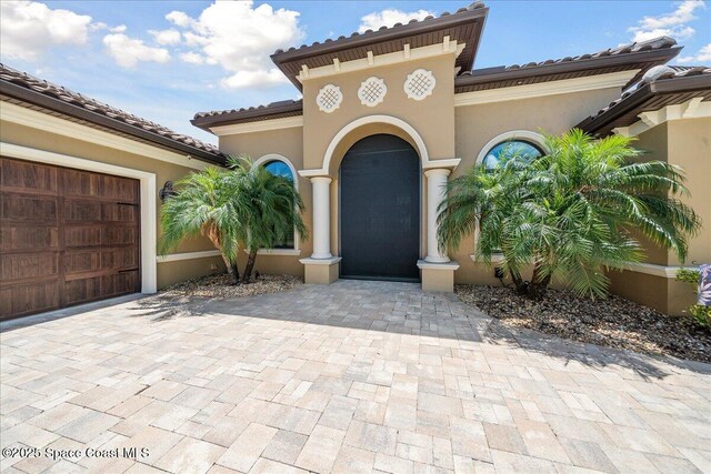 4464 Preservation Cir, Melbourne, FL 32934 - doorway to property with stucco siding, a tiled roof, driveway, and an attached garage