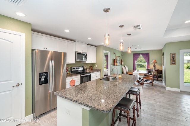 950 Douglas St SE, Palm Bay, FL 32909 - kitchen featuring appliances with stainless steel finishes, a center island with sink, white cabinets, a breakfast bar area, and recessed lighting