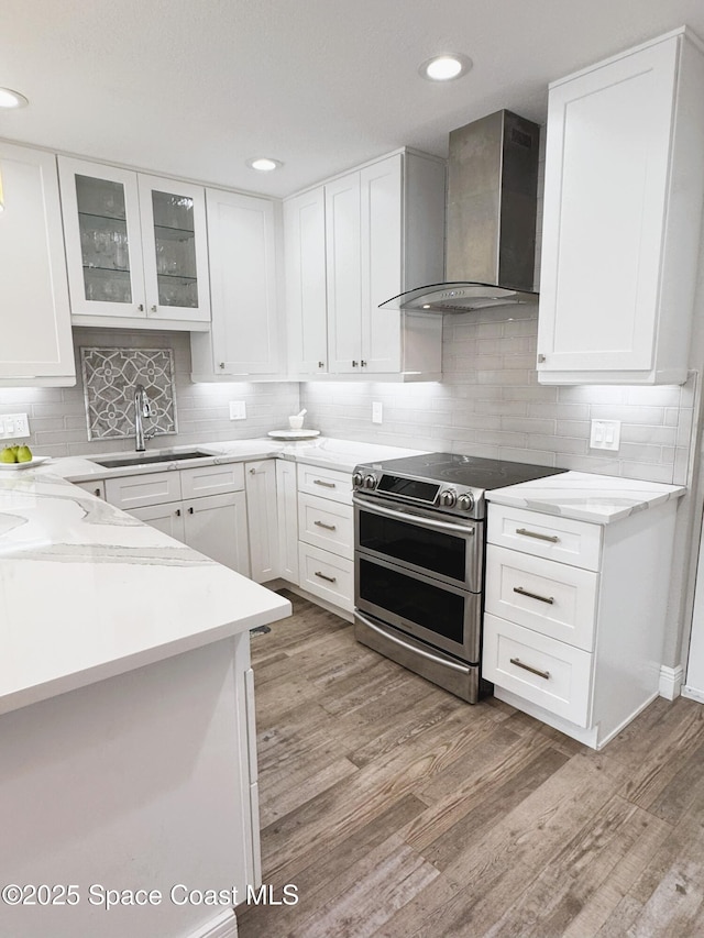 225 Buccaneer Ave Unit C2-207, Merritt Island, FL 32952 - kitchen with wall chimney exhaust hood, electric range, light wood-style flooring, white cabinetry, and recessed lighting