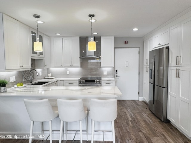 225 Buccaneer Ave Unit C2-207, Merritt Island, FL 32952 - kitchen with stainless steel appliances, wall chimney exhaust hood, a peninsula, white cabinetry, and recessed lighting