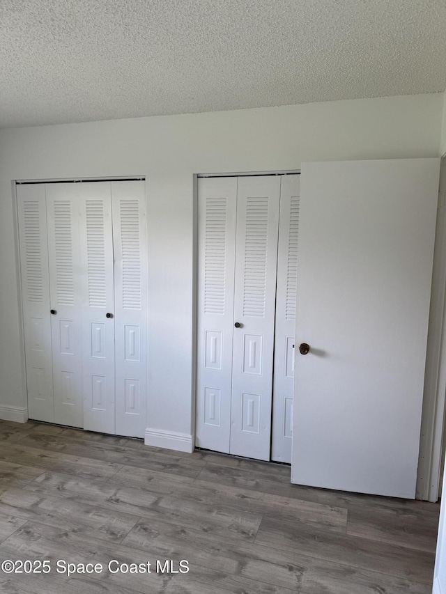 1112 Wabash Rd SE, Palm Bay, FL 32909 - unfurnished bedroom with two closets, wood finished floors, and a textured ceiling