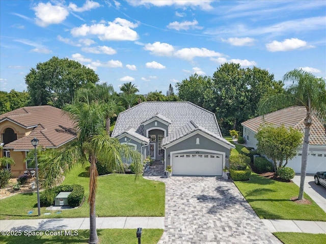 984 Wimbledon Dr, Melbourne, FL 32940 - view of front of property with an attached garage, a front yard, decorative driveway, stucco siding, and a tiled roof