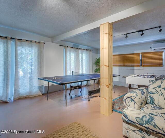 936 Santa Cruz Rd, Cocoa Beach, FL 32931 - playroom featuring a textured ceiling, an AC wall unit, track lighting, healthy amount of natural light, and finished concrete flooring