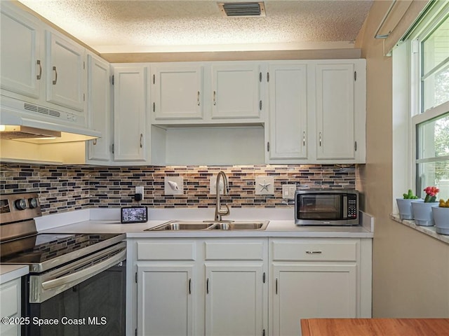 26 Pine Arbor Ln Unit 205, Vero Beach, FL 32962 - kitchen featuring appliances with stainless steel finishes, under cabinet range hood, light countertops, white cabinetry, and a textured ceiling