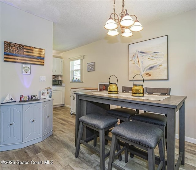 26 Pine Arbor Ln Unit 205, Vero Beach, FL 32962 - dining area featuring a chandelier, light wood finished floors, and a textured ceiling