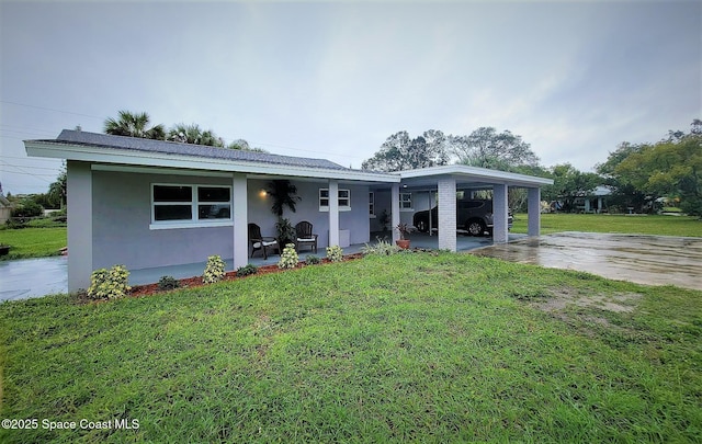 2309 Dairy Rd, Melbourne, FL 32904 - view of front of house with a front yard, stucco siding, driveway, and an attached carport