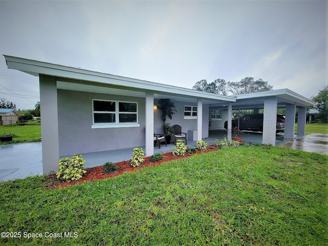 2309 Dairy Rd, Melbourne, FL 32904 - view of front of home featuring an attached carport, a front yard, covered porch, and stucco siding