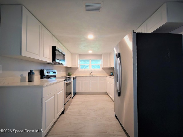 2309 Dairy Rd, Melbourne, FL 32904 - kitchen featuring appliances with stainless steel finishes, light marble finish floors, light countertops, white cabinets, and recessed lighting