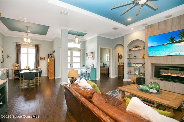 7354 Lucaya Ct, Melbourne, FL 32940 - living room featuring a raised ceiling, a ceiling fan, built in shelves, dark wood-type flooring, and crown molding