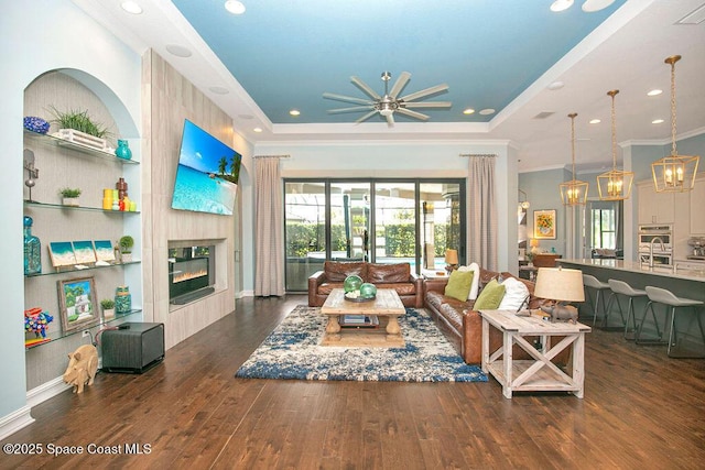7354 Lucaya Ct, Melbourne, FL 32940 - living area featuring a raised ceiling, a tile fireplace, hardwood / wood-style flooring, a ceiling fan, and a chandelier
