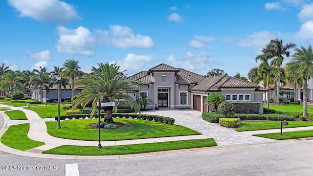 7354 Lucaya Ct, Melbourne, FL 32940 - mediterranean / spanish-style house featuring a garage, a front lawn, decorative driveway, stucco siding, and a tiled roof
