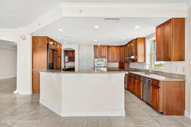 225 N Atlantic Ave Unit 603, Cocoa Beach, FL 32931 - kitchen with appliances with stainless steel finishes, a kitchen bar, light stone counters, brown cabinets, and crown molding