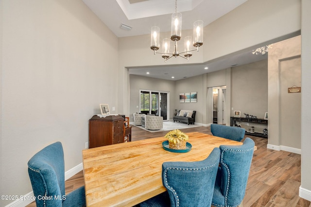 4554 Preservation Cir, Melbourne, FL 32934 - dining space featuring a chandelier, wood finished floors, a tray ceiling, and a high ceiling
