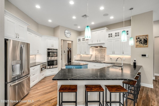4554 Preservation Cir, Melbourne, FL 32934 - kitchen featuring appliances with stainless steel finishes, light wood-type flooring, a kitchen breakfast bar, white cabinetry, and dark countertops