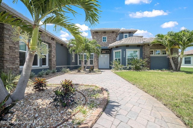 4554 Preservation Cir, Melbourne, FL 32934 - view of front facade with stucco siding, a front yard, a tiled roof, and stone siding