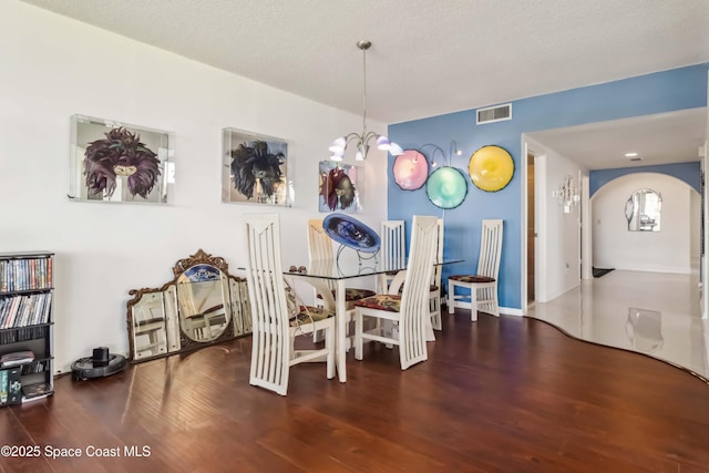 750 N Atlantic Ave Unit 203, Cocoa Beach, FL 32931 - dining space featuring wood finished floors, arched walkways, a chandelier, and a textured ceiling