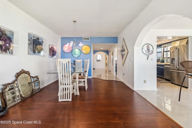 750 N Atlantic Ave Unit 203, Cocoa Beach, FL 32931 - dining space with arched walkways, a chandelier, and wood finished floors