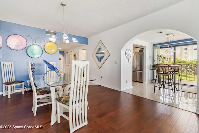 750 N Atlantic Ave Unit 203, Cocoa Beach, FL 32931 - dining area featuring arched walkways, a chandelier, and wood finished floors