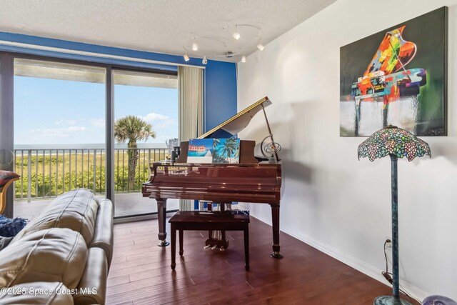 750 N Atlantic Ave Unit 203, Cocoa Beach, FL 32931 - living area featuring healthy amount of natural light, wood finished floors, a water view, and track lighting