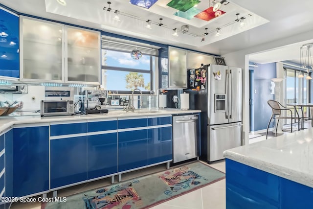 750 N Atlantic Ave Unit 203, Cocoa Beach, FL 32931 - kitchen with appliances with stainless steel finishes, blue cabinets, healthy amount of natural light, and light tile patterned floors