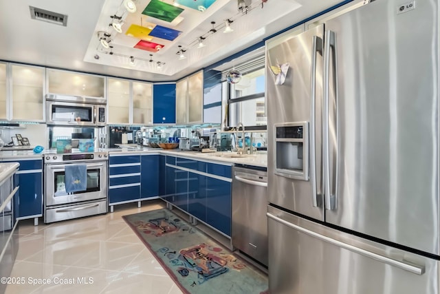 750 N Atlantic Ave Unit 203, Cocoa Beach, FL 32931 - kitchen with stainless steel appliances, blue cabinetry, light countertops, rail lighting, and a raised ceiling