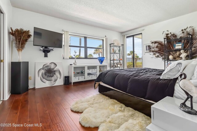 750 N Atlantic Ave Unit 203, Cocoa Beach, FL 32931 - bedroom with access to exterior, multiple windows, hardwood / wood-style flooring, and a textured ceiling