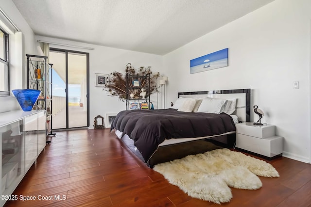 750 N Atlantic Ave Unit 203, Cocoa Beach, FL 32931 - bedroom with hardwood / wood-style floors, access to exterior, and a textured ceiling