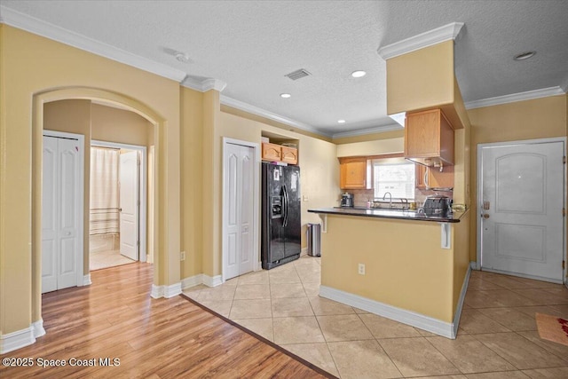 2097 Hidden Grove Ln Unit 106, Merritt Island, FL 32953 - kitchen with black fridge, dark countertops, crown molding, a peninsula, and arched walkways