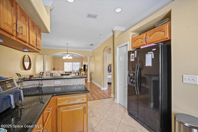 2097 Hidden Grove Ln Unit 106, Merritt Island, FL 32953 - kitchen featuring black fridge, ornate columns, crown molding, arched walkways, and brown cabinetry