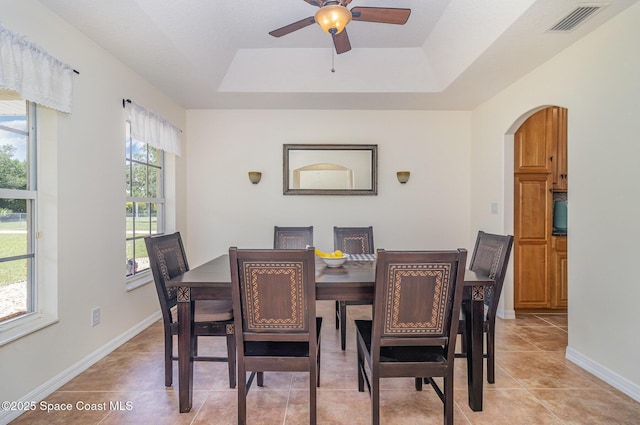 690 Grant Rd, Palm Bay, FL 32909 - dining space featuring arched walkways, a ceiling fan, a raised ceiling, and light tile patterned floors