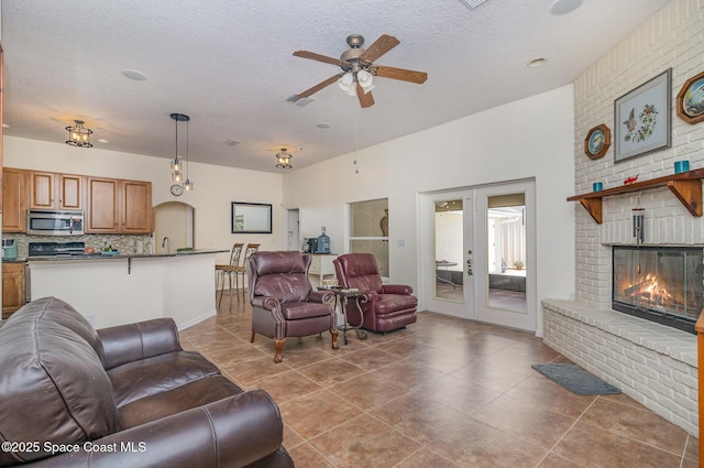 690 Grant Rd, Palm Bay, FL 32909 - living area with ceiling fan, a textured ceiling, french doors, a fireplace, and tile patterned floors