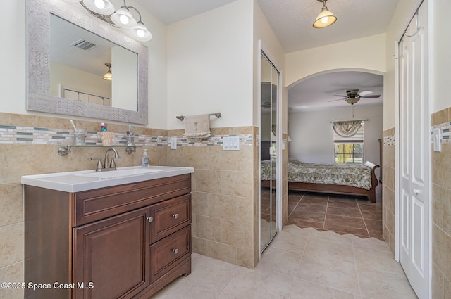 690 Grant Rd, Palm Bay, FL 32909 - bathroom with ensuite bath, tile walls, vanity, ceiling fan, and a wainscoted wall
