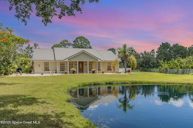 690 Grant Rd, Palm Bay, FL 32909 - back of house at dusk with a yard, covered porch, a metal roof, and a water view
