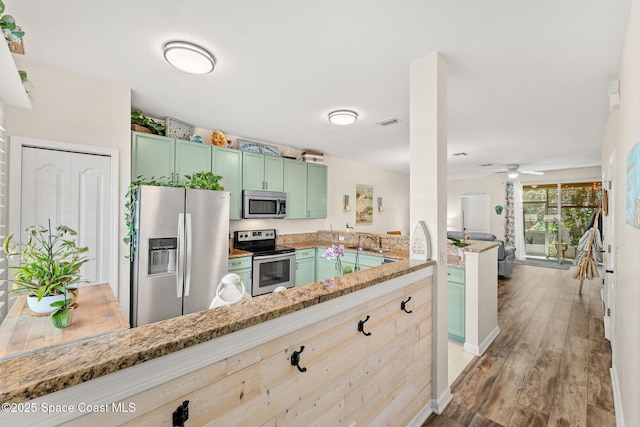 3498 Cutty Sark Way, Indialantic, FL 32903 - kitchen with stainless steel appliances, green cabinetry, light stone countertops, and a peninsula