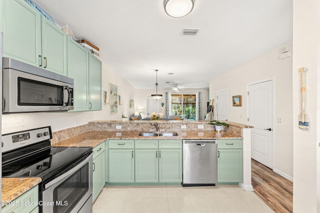 3498 Cutty Sark Way, Indialantic, FL 32903 - kitchen with appliances with stainless steel finishes, green cabinetry, ceiling fan, a peninsula, and light stone counters