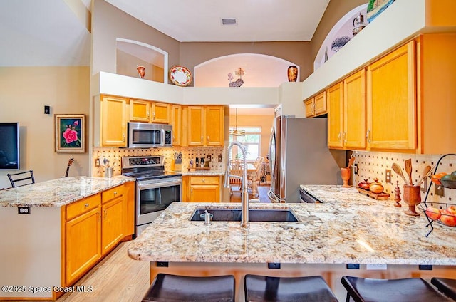 4204 Long Leaf Dr, Melbourne, FL 32940 - kitchen with stainless steel appliances, a peninsula, light stone countertops, a kitchen bar, and decorative backsplash