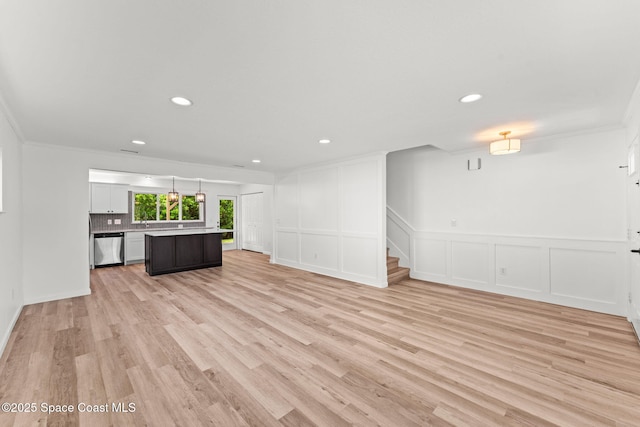 332 Nikomas Way, Melbourne Beach, FL 32951 - unfurnished living room with crown molding, stairs, a decorative wall, light wood-style floors, and recessed lighting