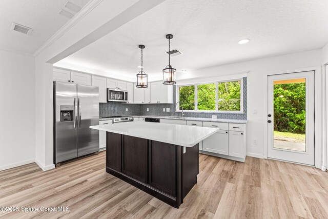 332 Nikomas Way, Melbourne Beach, FL 32951 - kitchen with appliances with stainless steel finishes, light countertops, light wood-style floors, a center island, and recessed lighting