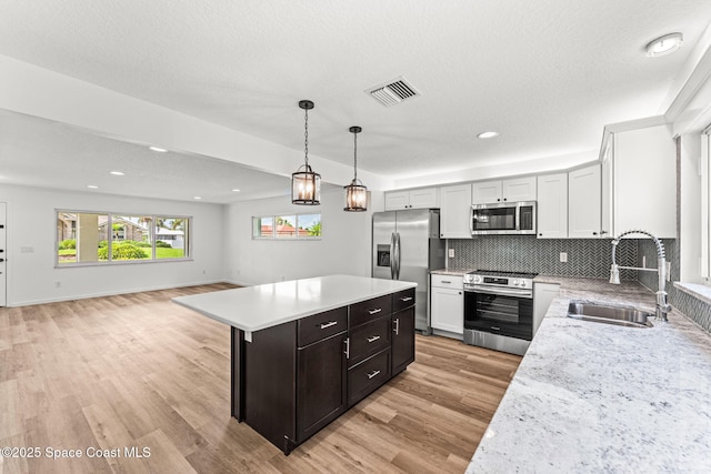 332 Nikomas Way, Melbourne Beach, FL 32951 - kitchen with stainless steel appliances, a center island, light wood-style flooring, open floor plan, and tasteful backsplash