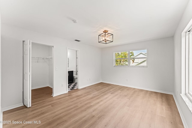 332 Nikomas Way, Melbourne Beach, FL 32951 - unfurnished bedroom featuring light wood-style flooring, a chandelier, a walk in closet, and a closet