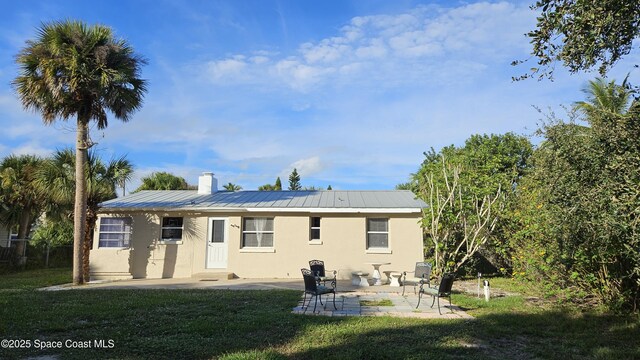 109 Fontaine St, Melbourne Beach, FL 32951 - rear view of house featuring stucco siding, a chimney, a yard, and a patio