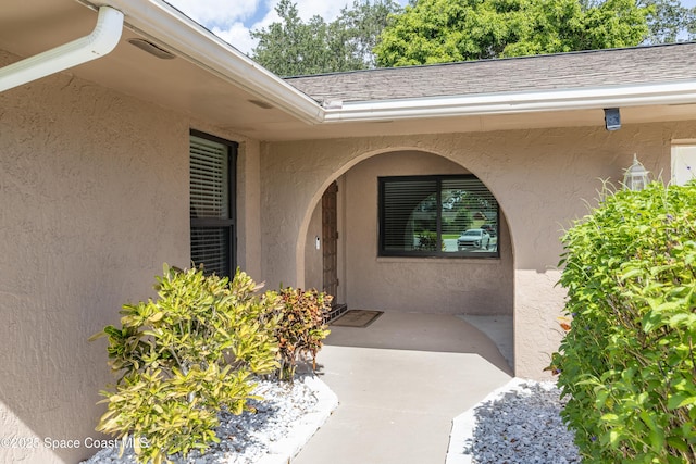 716 Endicott Rd, Melbourne, FL 32940 - view of exterior entry with stucco siding, a patio area, and a shingled roof
