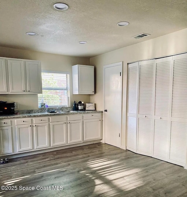 3717 Pinewood Dr NE Unit 12, Palm Bay, FL 32905 - kitchen with dark wood finished floors, a textured ceiling, white cabinetry, recessed lighting, and stone counters