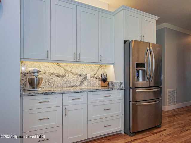 406 9th Ct, Vero Beach, FL 32962 - kitchen featuring stainless steel fridge with ice dispenser, tasteful backsplash, white cabinets, light wood-type flooring, and light stone counters