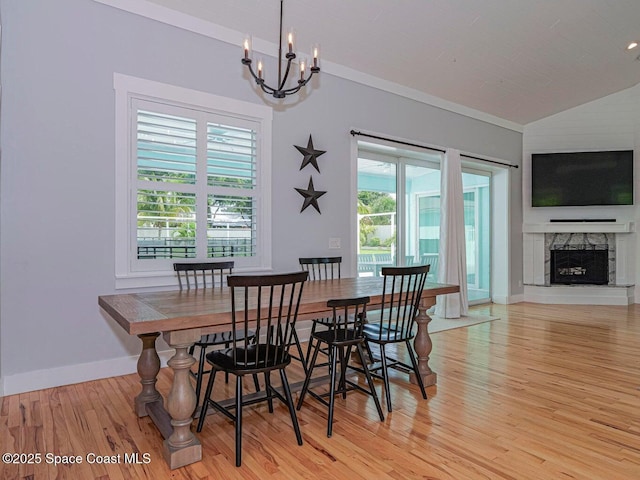 406 9th Ct, Vero Beach, FL 32962 - dining space featuring a chandelier, light wood-style floors, vaulted ceiling, and a stone fireplace