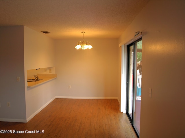 292 San Juan Cir, Melbourne, FL 32935 - unfurnished dining area featuring wood finished floors, a chandelier, and a textured ceiling