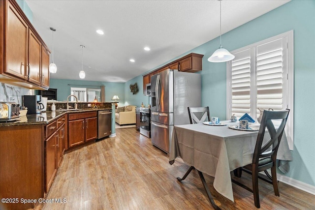 1787 Attilburgh Blvd, West Melbourne, FL 32904 - kitchen featuring appliances with stainless steel finishes, light wood finished floors, hanging light fixtures, brown cabinetry, and open floor plan
