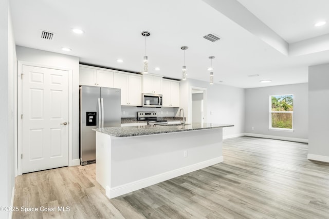 2181 Wagonwheel Ave SE, Palm Bay, FL 32909 - kitchen with stainless steel appliances, light wood-style floors, dark stone countertops, white cabinets, and recessed lighting