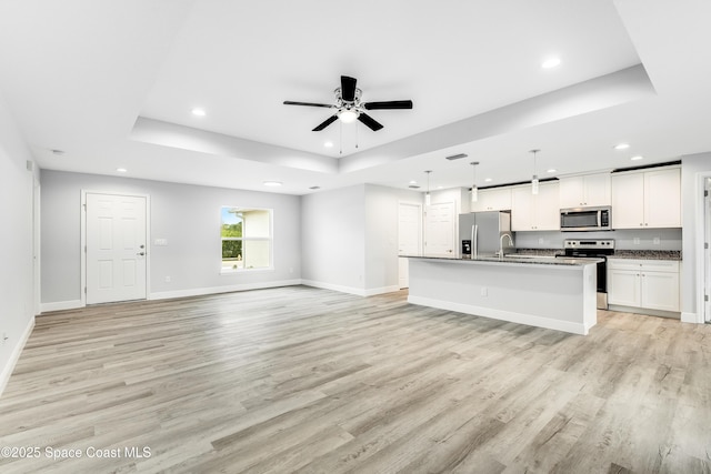 2181 Wagonwheel Ave SE, Palm Bay, FL 32909 - unfurnished living room featuring a tray ceiling, recessed lighting, light wood-type flooring, and a ceiling fan