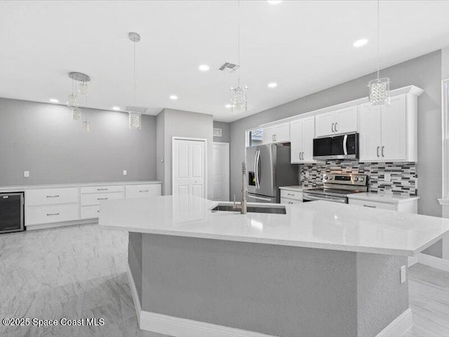 3358 Nancy St, West Melbourne, FL 32904 - kitchen featuring appliances with stainless steel finishes, white cabinets, backsplash, a large island with sink, and recessed lighting